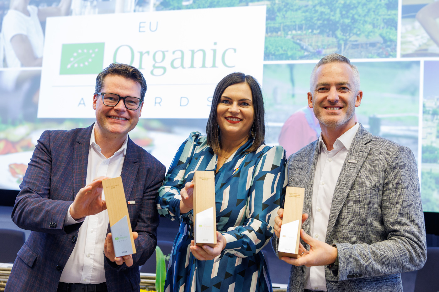 a lady flanked by 2 men, smiling, each holding their EU Organic Award