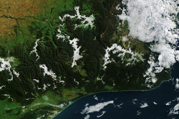 Wide patches of fog fill river valleys cutting through rugged, dark green mountains in eastern Victoria.