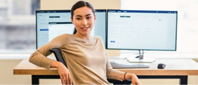 デスクトップのセットアップの前に座って、カメラを見ている女性