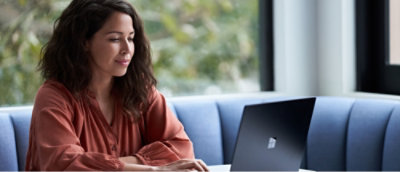 A person holding a laptop and wearing glasses with a red shirt.
