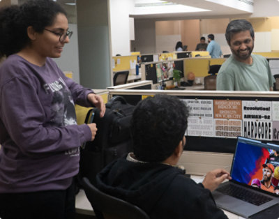 A person and another person looking at a computer