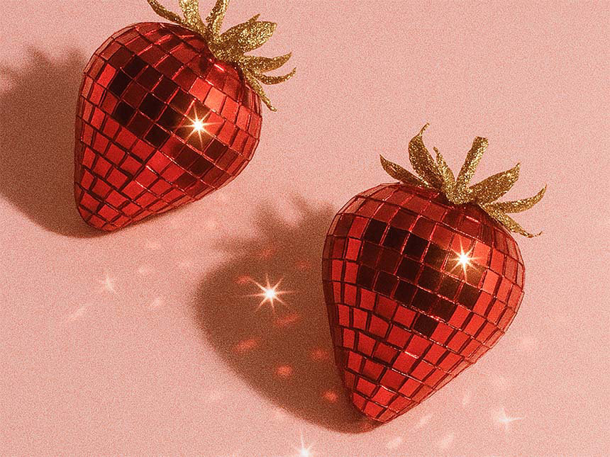 Zwei Erdbeeren, die wie rote Discokugeln gestaltet sind, mit reflektierenden Mosaikfacetten und glitzernden goldenen Blättern auf einem weichen, rosafarbenen Hintergrund