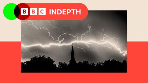 A lightning fork captured at night with a church tower and trees silhouetted in the foreground