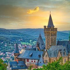 Schloss Wernigerode vor goldenem Himmel, im Hintergrund Hügel