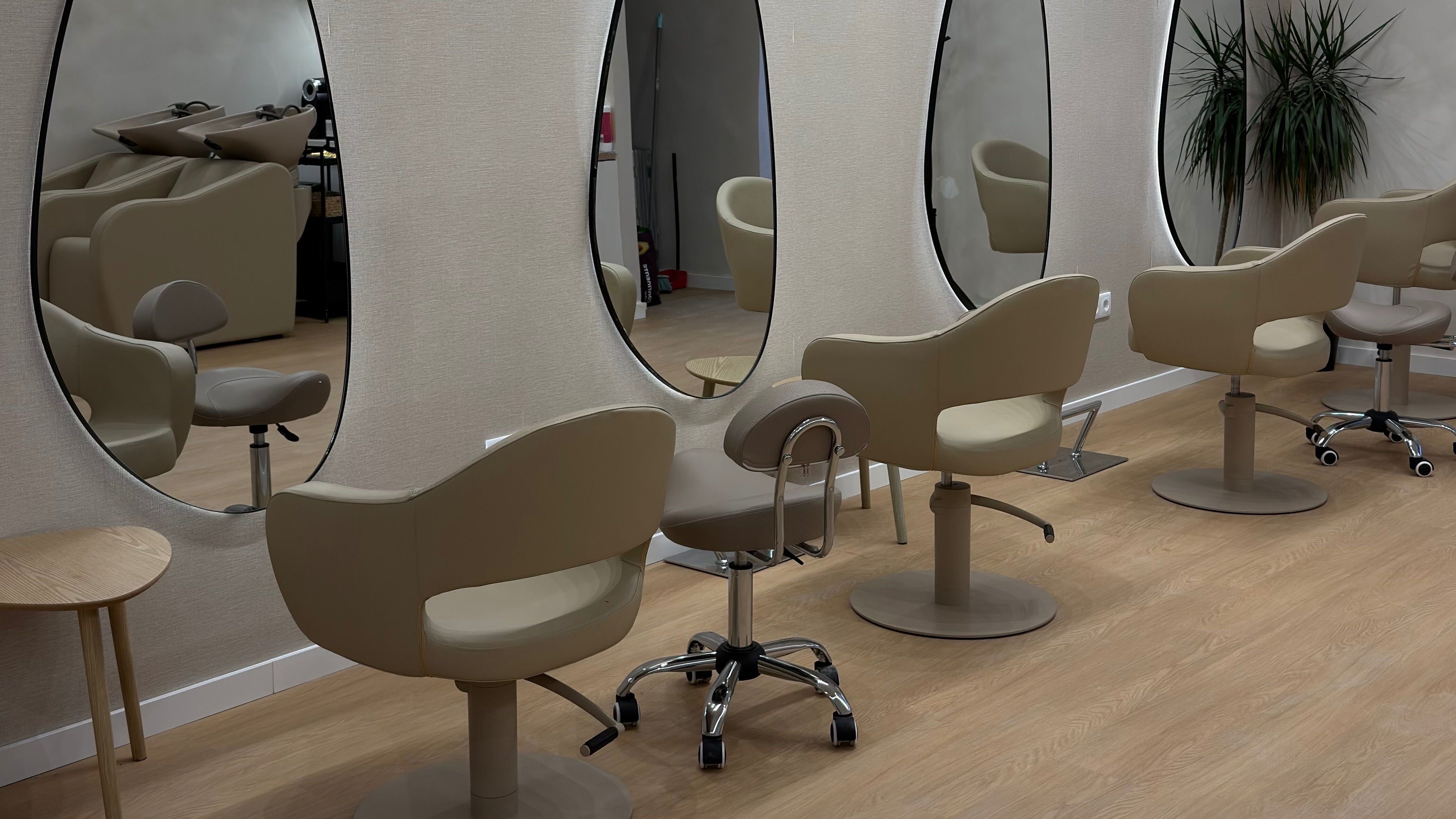 Interior moderno do salão G Beauty Concept em Porto, PT, com cadeiras de salão elegantes e espelhos ovais.