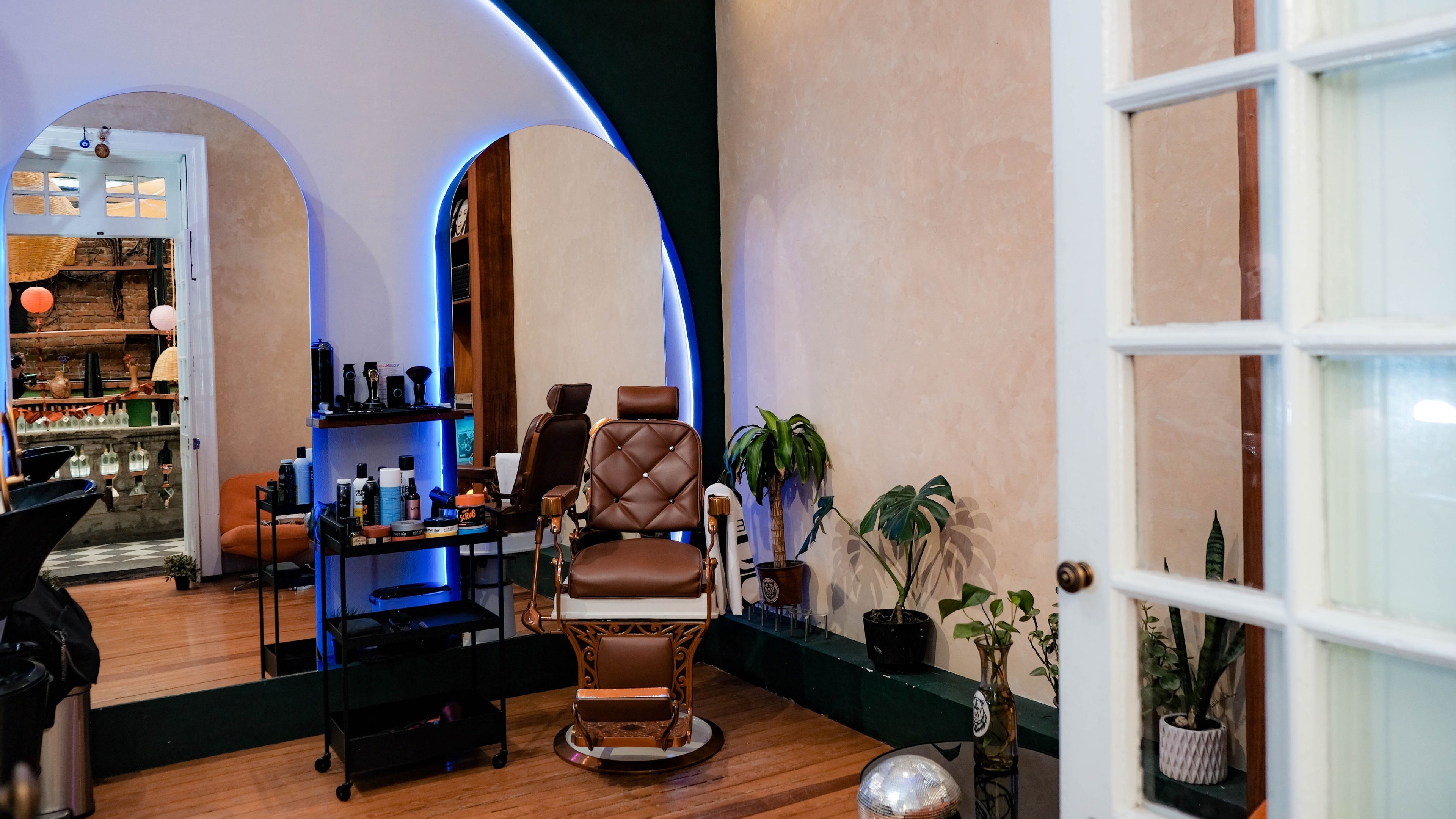 Interior acogedor de Grizzly Barber Club en Ciudad De México, con silla de barbero clásica y plantas decorativas.