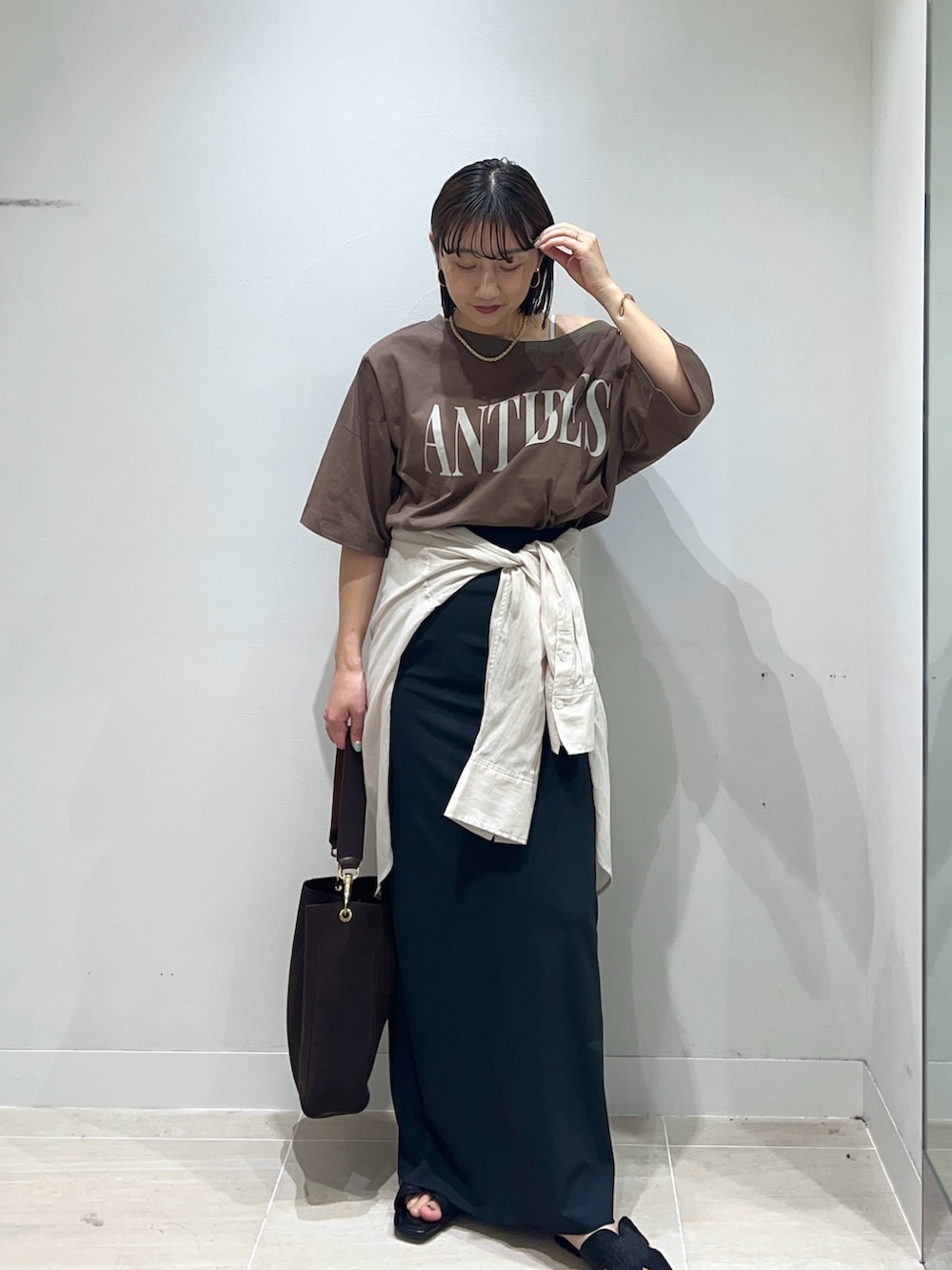ブラウン系のTシャツ/カットソー、ベージュ系のシャツ/ブラウス、ブラック系のスカートを着用したレディースの春コーディネートの3枚目の写真