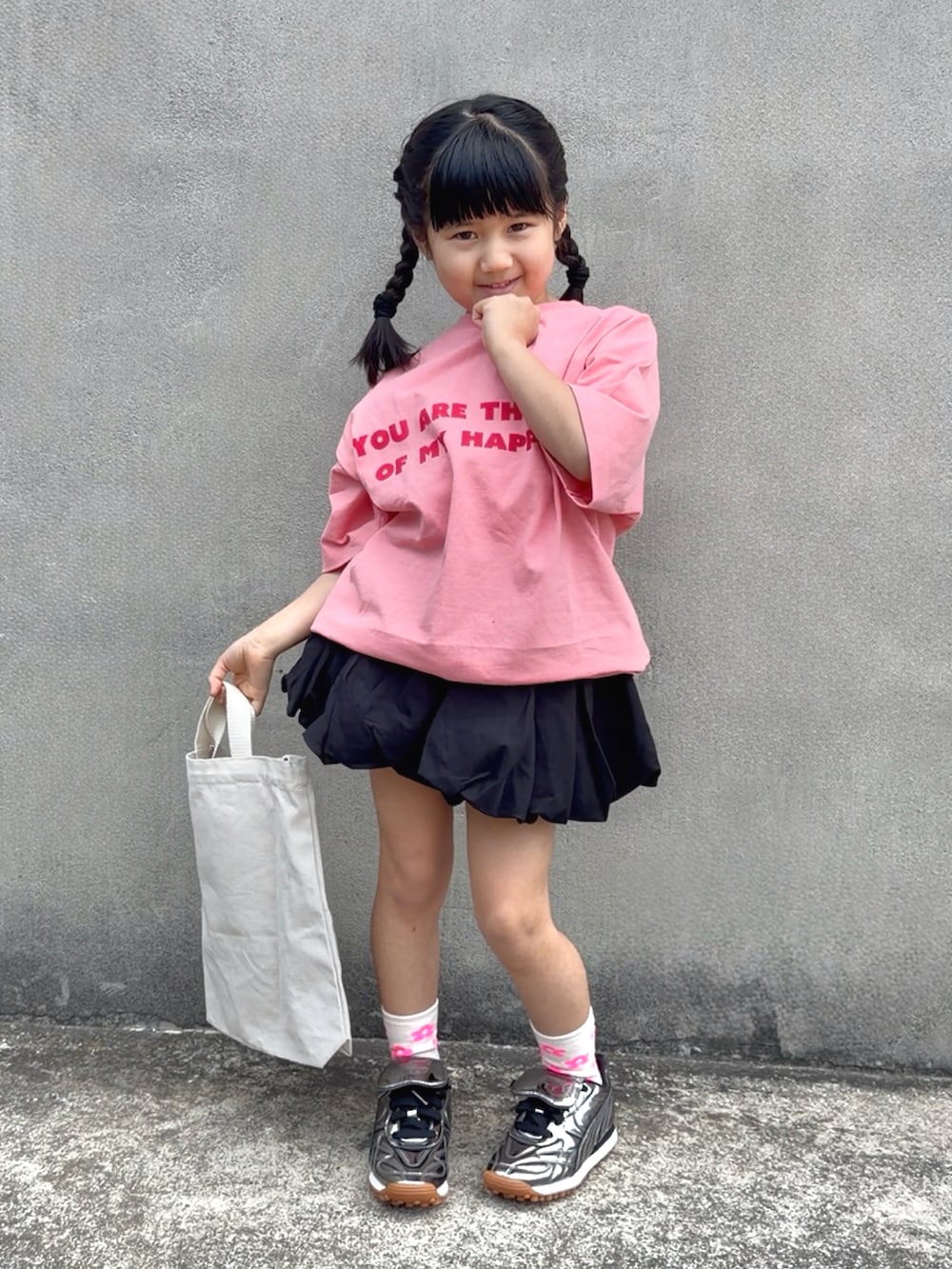 ピンク系のTシャツ/カットソー、ホワイト系のトートバッグ、ブラック系のスカートを着用したキッズの春コーディネートの3枚目の写真