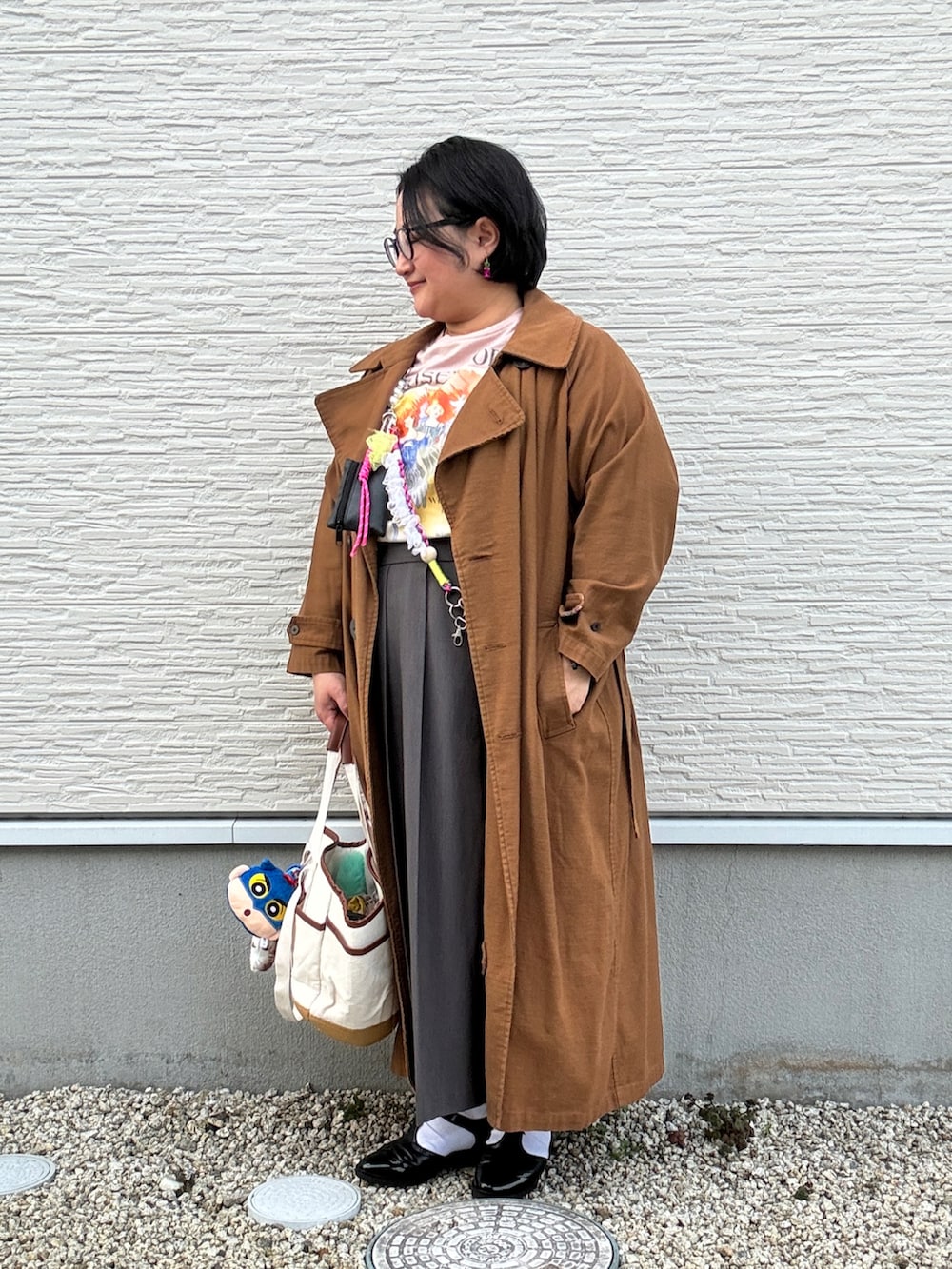ブラウン系のトレンチコート、ピンク系のTシャツ/カットソー、グレー系のスカートを着用したレディースの冬コーディネートの2枚目の写真