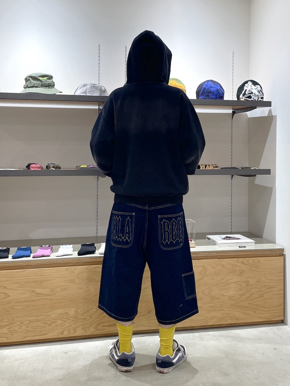 ブラック系のパーカー、ブルー系のデニムパンツ、ホワイト系のハットを着用したメンズの春コーディネートの3枚目の写真