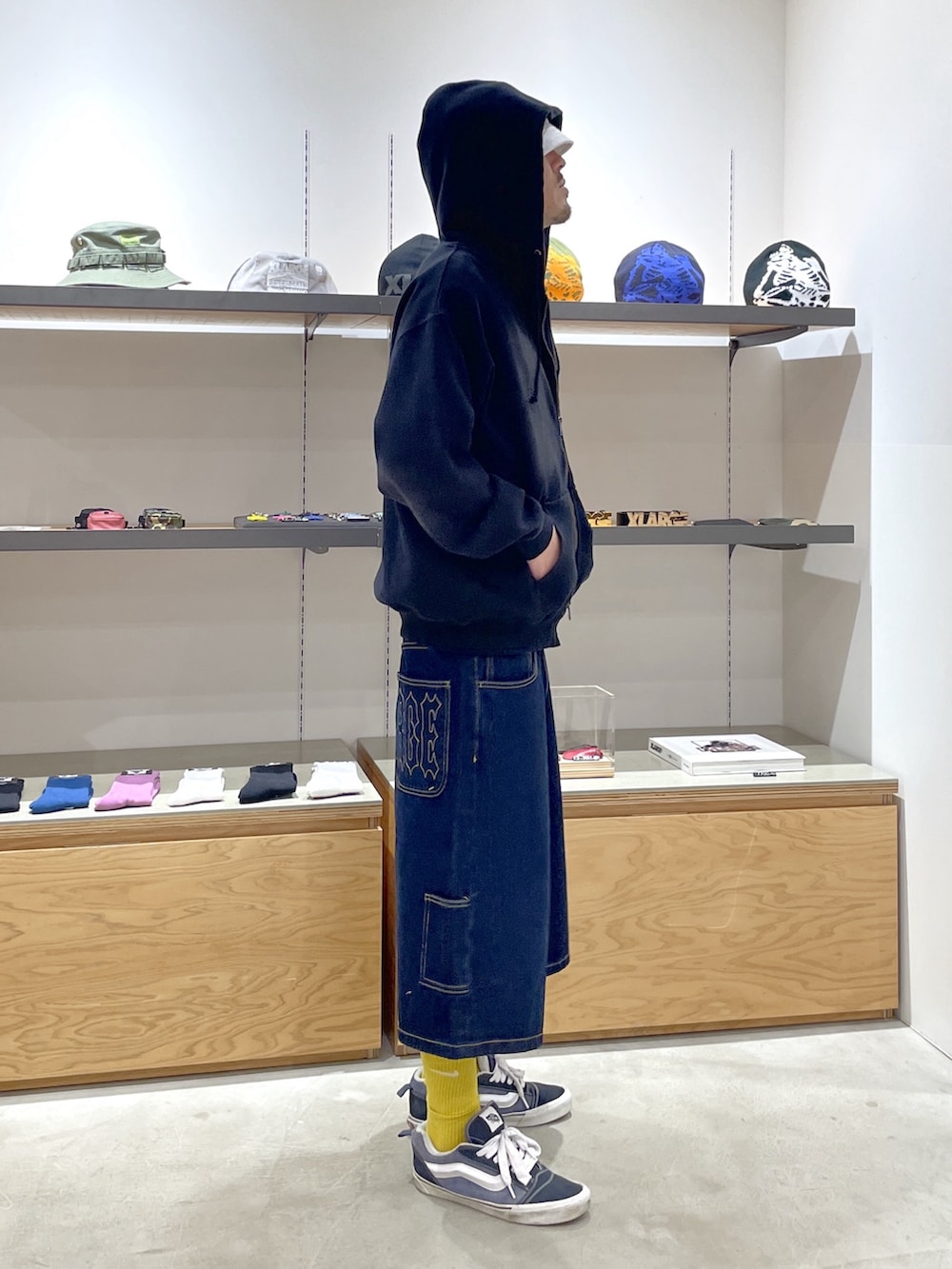 ブラック系のパーカー、ブルー系のデニムパンツ、ホワイト系のハットを着用したメンズの春コーディネートの2枚目の写真