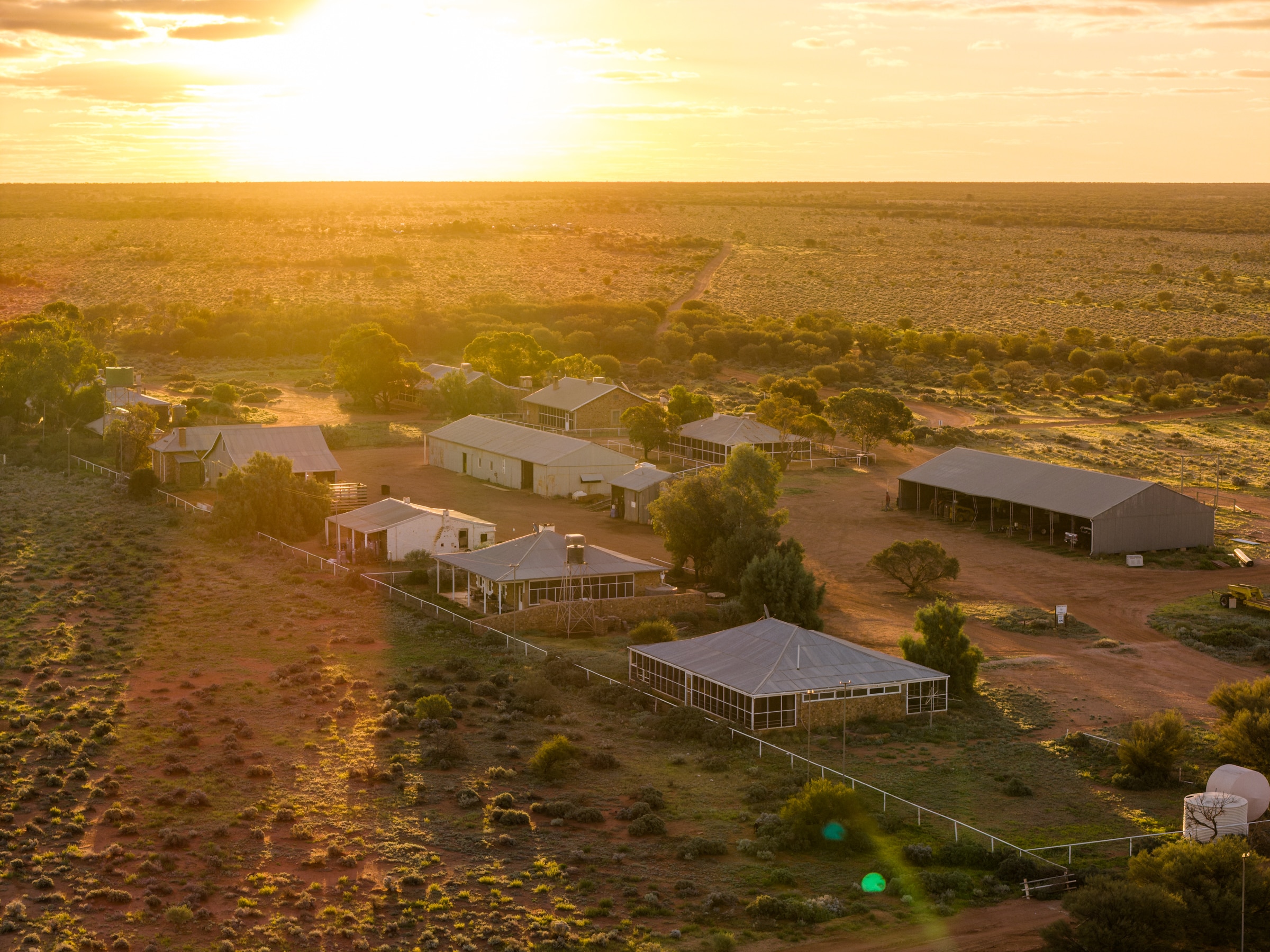 Drone photo of the large homestead of an outback station at sunset.