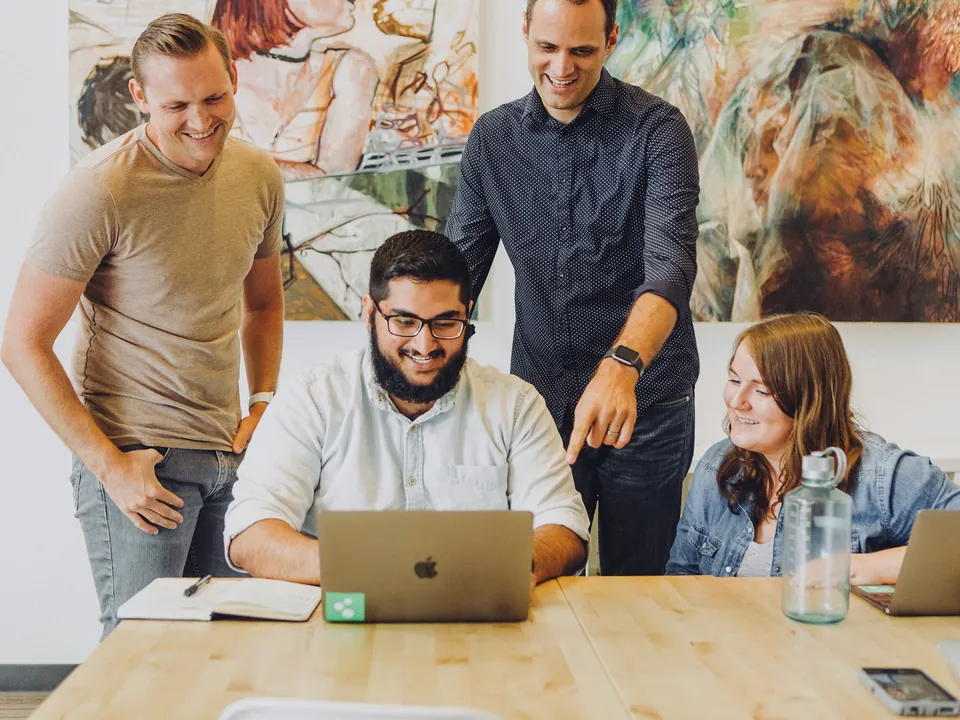 A small software team laughing together round a laptop