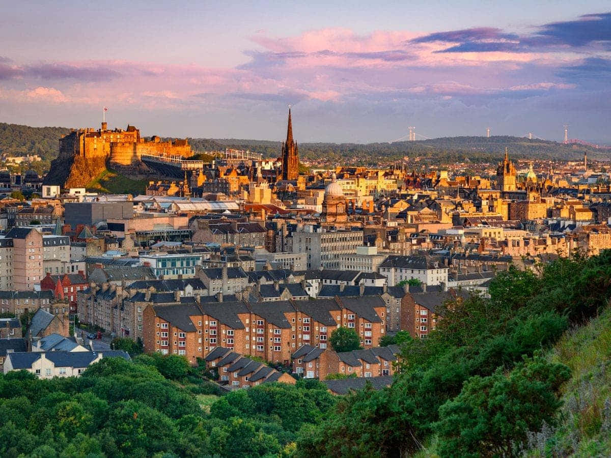 Das Bild zeigt die atemberaubende und detailreiche Panoramaansicht von Schottlands Hauptstadt Edinburgh. Die ikonischen Wahrzeichen der Stadt, historischen Stätten und die schöne Architektur sind alle in diesem hochwertigen Foto festgehalten. Der Himmel weist eine dynamische Farbpalette von dunklen, stimmungsvollen Blautönen bis zu sanften Pastellrosa- und Lilatönen auf und verleiht der Stadt eine dramatische, aber dennoch ruhige Atmosphäre. Die dramatische Skyline, königlichen Stätten, sanften Hügel und alten Gebäude wurden alle von einem hohen Aussichtspunkt mit außergewöhnlicher Liebe zum Detail aufgenommen. Dieser definitive Schnappschuss von Edinburgh vermittelt ein Gefühl für die reiche Geschichte, lebendige Kultur und bedeutendes Erbe der Stadt. — Edinburgh Bild Wallpaper
