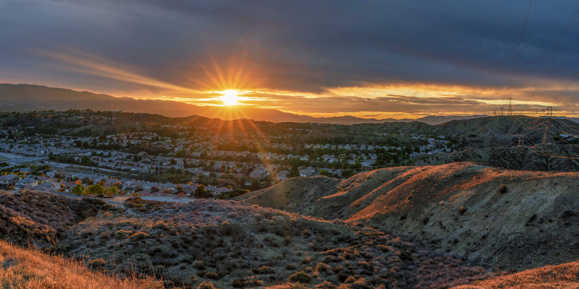 Sunset over suburban valley with rolling hills and dramatic clouds