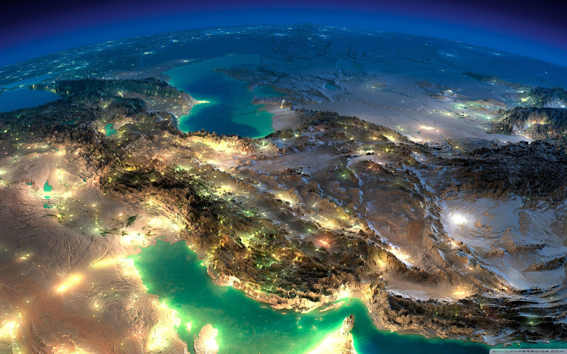 Night view of Earth showing glowing cities and turquoise oceans from space.