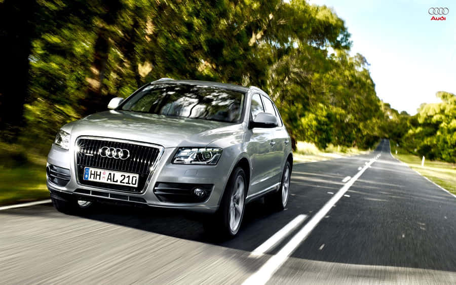 Cette superbe image haute résolution présente une Audi SQ5 glissant sans effort le long d'un tronçon de route pittoresque. Tombez amoureux de la combinaison élégante et frappante de luxe et de performances que seule une Audi SQ5 peut offrir. Parfait comme fond d'écran ou simplement pour admirer le design élégant et la puissance de l'Audi SQ5.