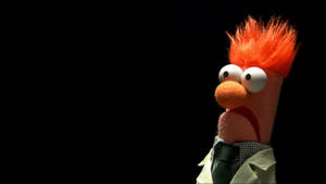 Fozzie Bear puppet with orange hair and checkered shirt against black background.