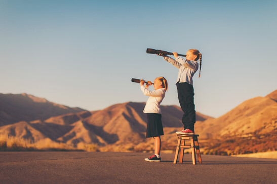 Due ragazzine scrutano l'orizzonte con il telescopio foto iStock.