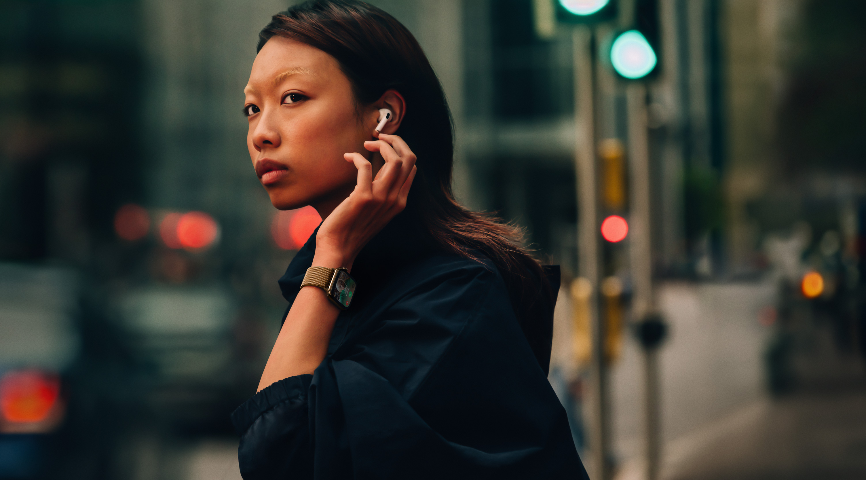 Žena na ulici nosi Apple Watch Series 10 i slušalice AirPods.