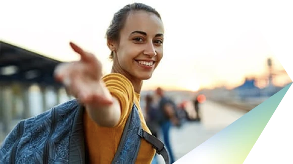 Woman in yellow blouse, smiling and reaching out her right hand towards the camera