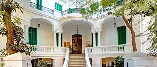 Weiße Villa mit Bäumen und Treppen