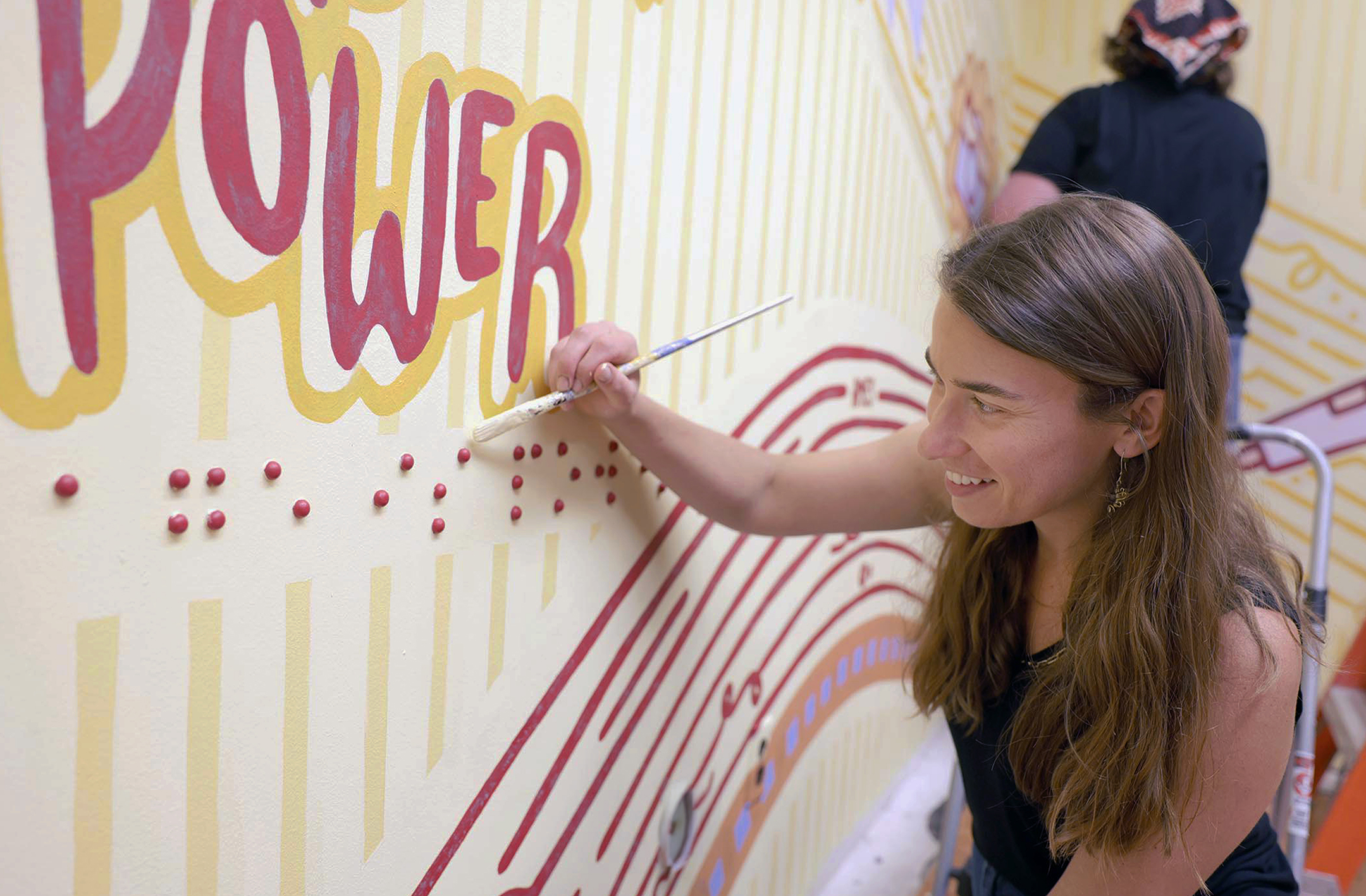 Design students painting the walls of a room with Cyclone colors and phrases.