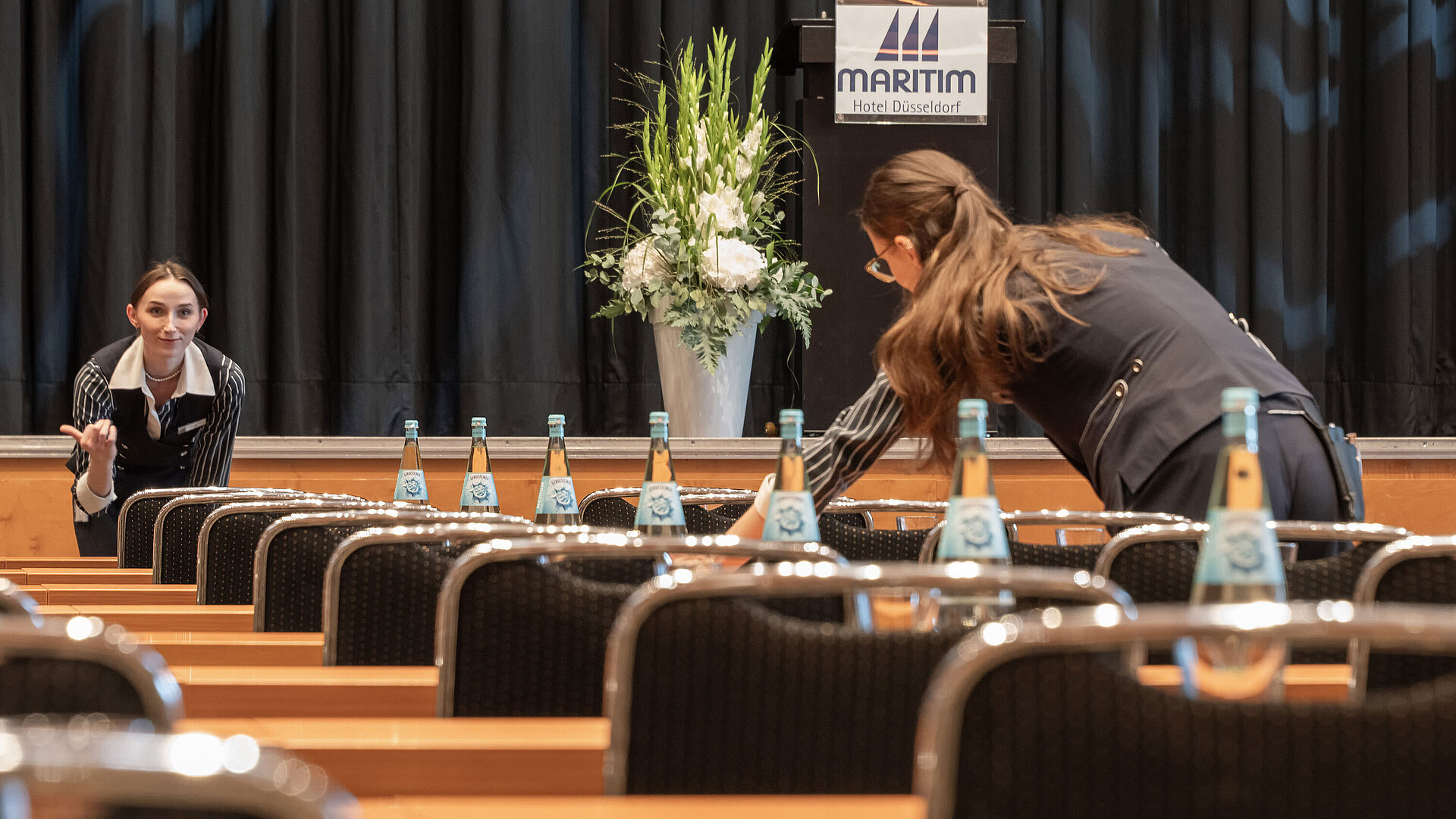 Tagungsservice Mitarbeiter bereiten Tagungsraum mit Bühne im Maritim Hotel Düsseldorf vor.