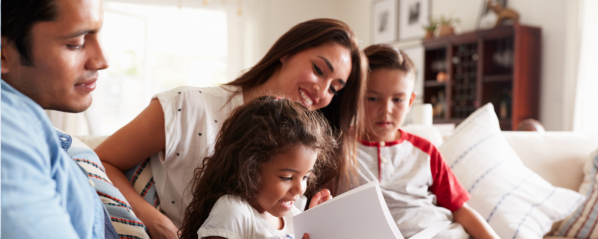 A Hispanic family looks at a book together. 