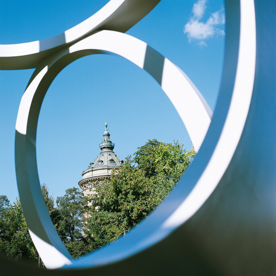 Der Mannheimer Wasserturm aus der Ferne inmitten von Bäumen