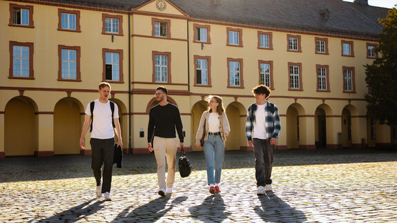Studierende laufen über den Schlossplatz am Unteren Schloss