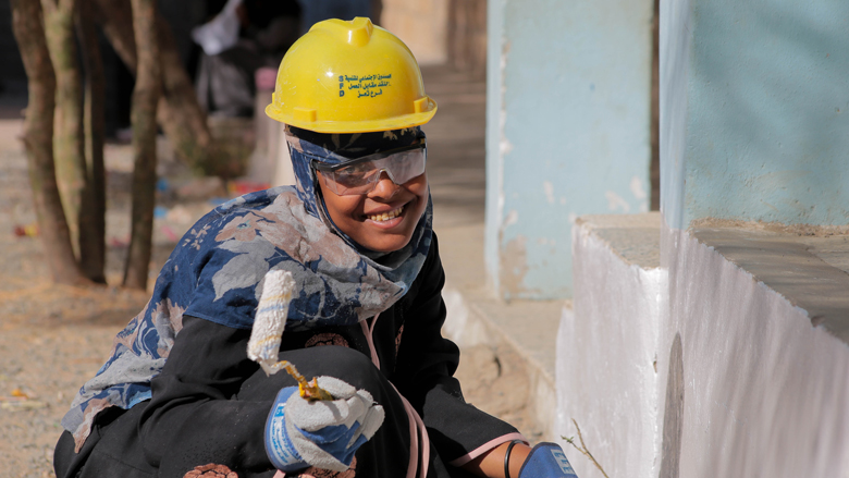 Wasila‎ uses the roller to paint the walls of the school. 