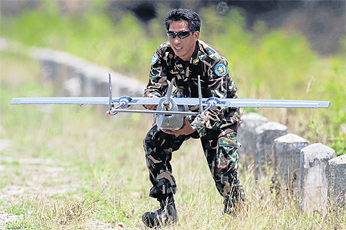 A forestry official launches a remote-controlled plane equipped with a camera. Officials are sending the planes to fly over a reservoir in the Kaeng Krachan National Park in Phetchaburi to search for a suspected white elephant spotted in the area recentl