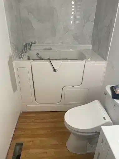 Delaware 13 Professional installation of a white compact walk-in bathtub with a built-in seat and chrome fixtures in a small bathroom.