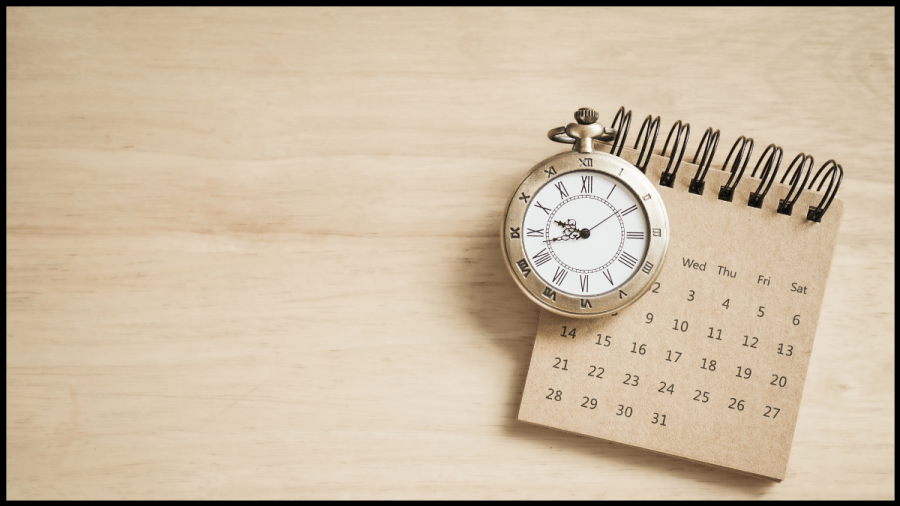 Photo of a calendar with a pocket watch on top.