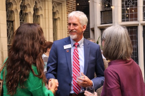 Man in jacket and tie shakes hands with two women