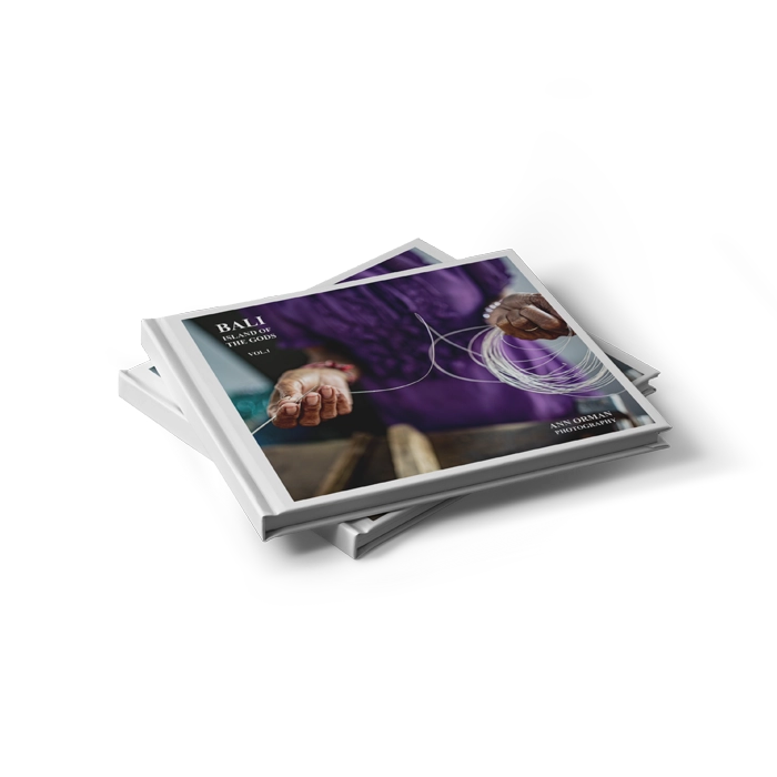 Une pile de deux livres photos au format paysage et à couverture rigide. La couverture montre une photo sombre d'une personne située à côté d'un grillage et avec un filtre rouge.