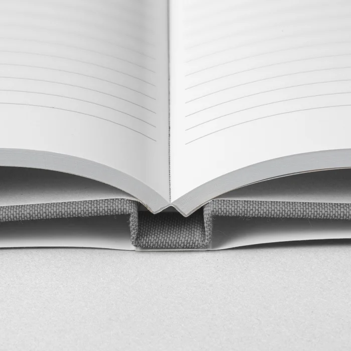 Cuaderno de tapa dura de lino con sobrecubierta abierto con páginas de rayas.