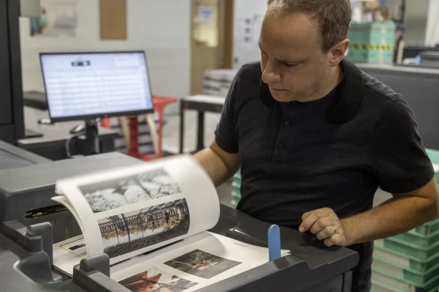 Person flipping through printed pages that will become a book in a print production facility.