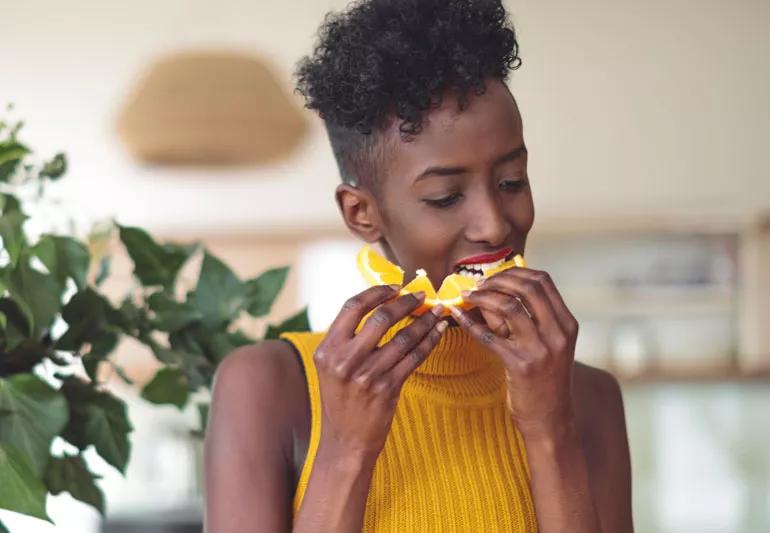 woman eating an orange to boost immunity