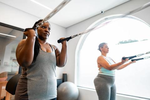 Two people using resistance bands at a gym