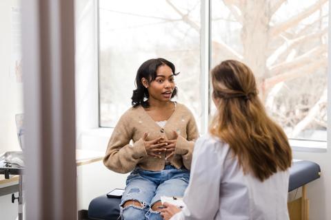 Teenager sitting on exam table talking to healthcare provider