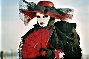 Woman with white mask, eyes outlined black, red hat and fan