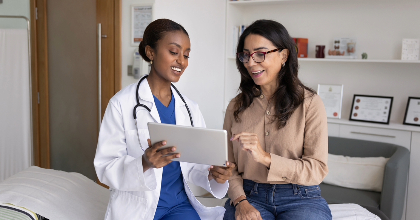 Automatic payment programs - A female doctor showing a tablet device to her female patient.