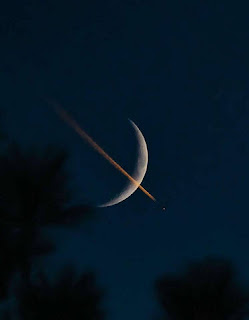 A Plane Transiting A Waxing Crescent Moon At Sunset