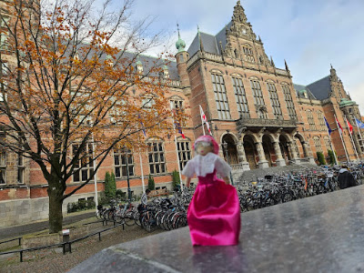 Etta Palm voor de Rijks Universiteit Groningen in de Broerstraat Het poppetje Etta Palm met op de achtergrond eerst heel veel fietsen en dan het universiteitsgebouw aan de Broerstraat