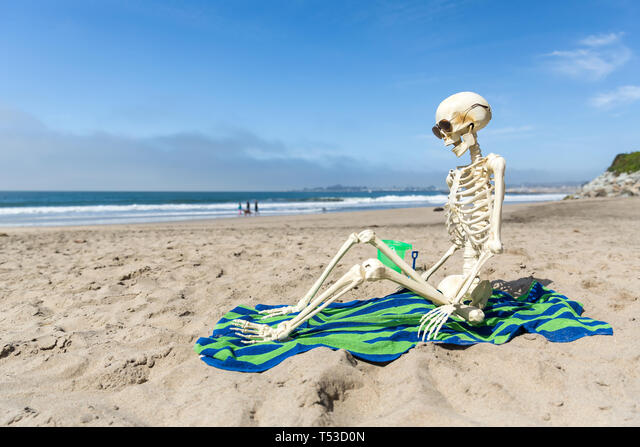 Skeleton sits on a beach towel relaxing in the sand Stock ...