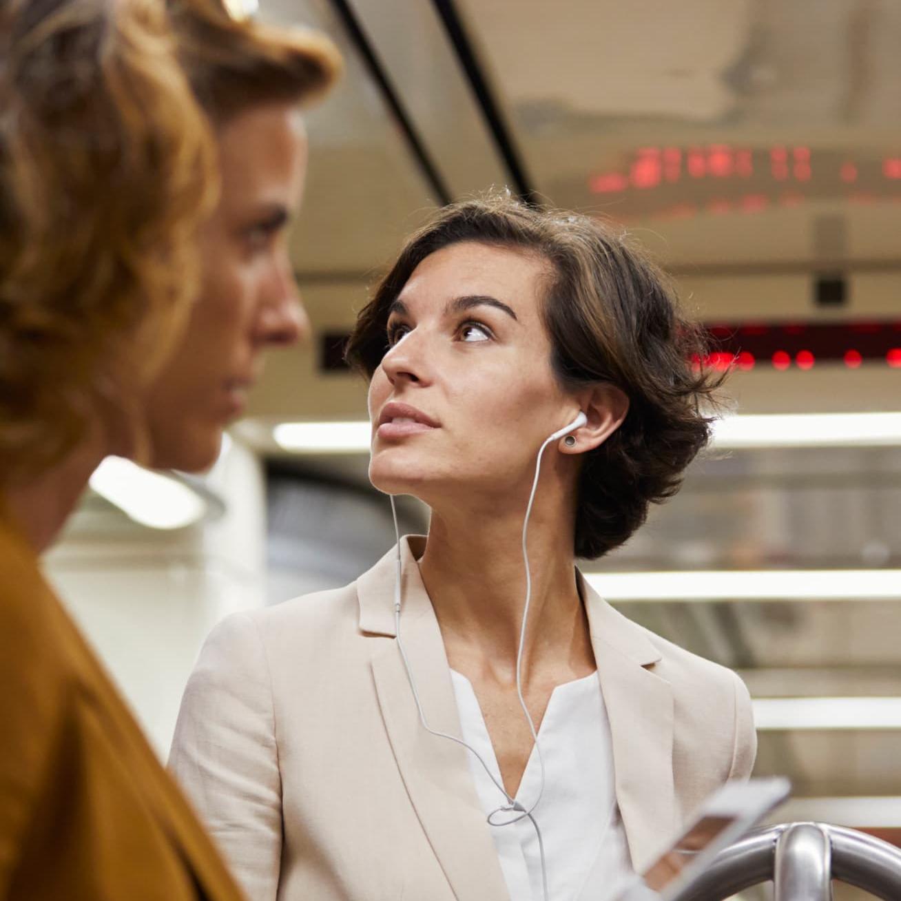 A woman listening to music on her headphones while commuting in a subway.