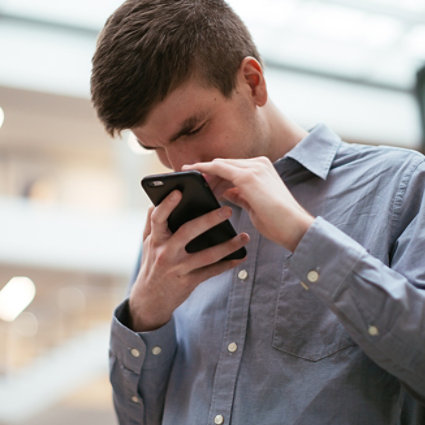 A man who has low vision, holds a mobile phone close to his face.