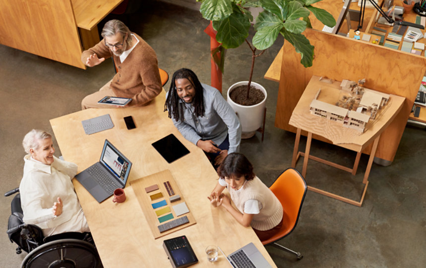 Colleagues sitting at a table waving to another person.